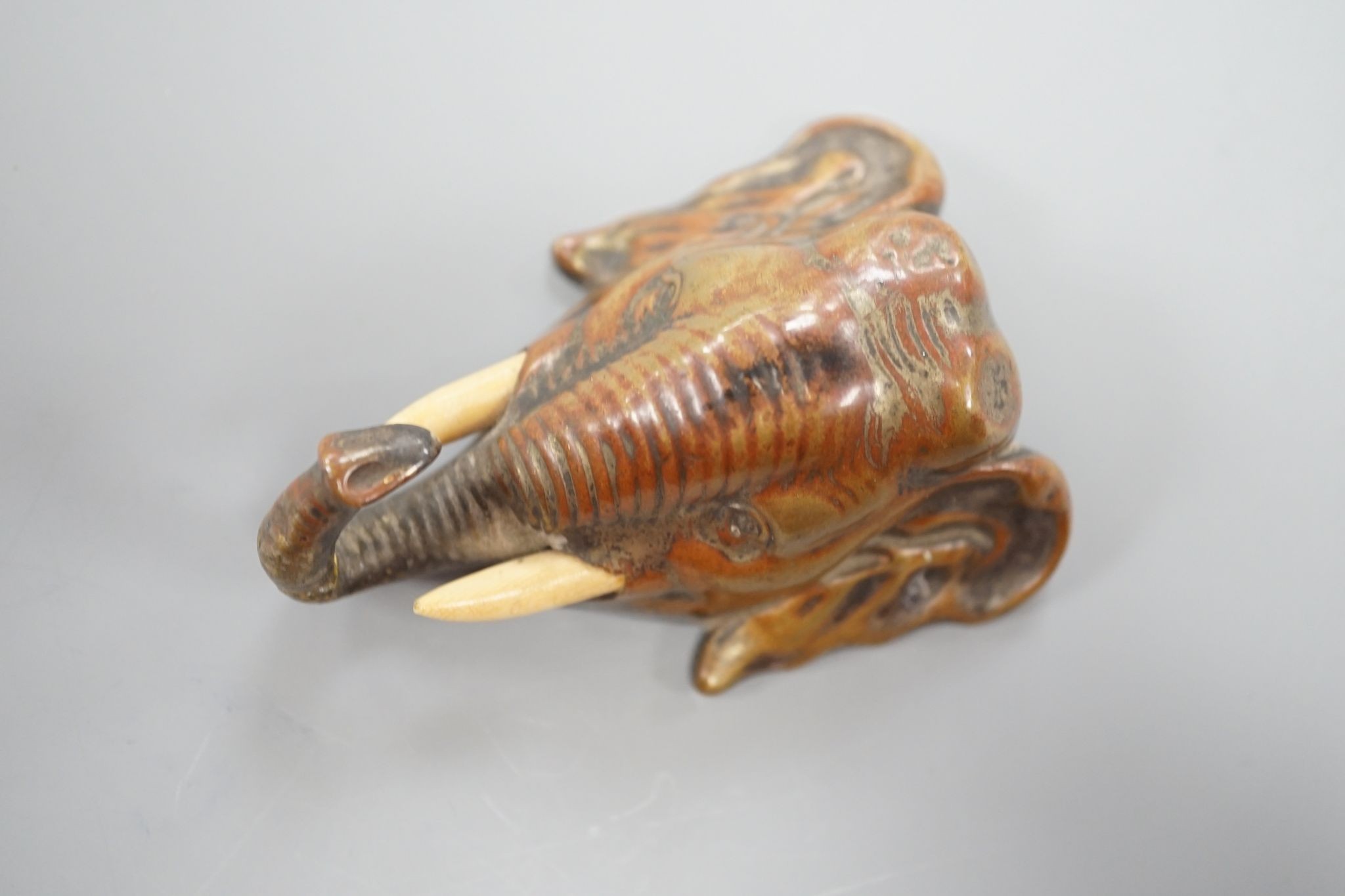 A small bronze elephant paperweight, ivory tusks, 9 cms long.